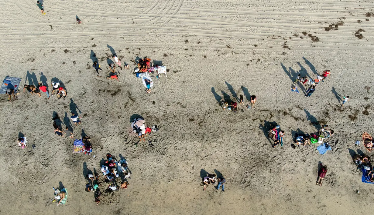 Pemandangan udara dari orang-orang di pantai di Playas de Tijuana dekat perbatasan AS-Meksiko di Tijuana, negara bagian Baja California, Meksiko, Sabtu (3/10/2020). Akhir pekan ini pantai di Playas de Tijuana dibuka kembali setelah ditutup sejak Maret lalu akibat Covid-19. (Guillermo Arias/AFP)