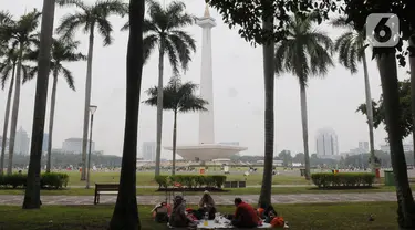 Pengunjung beristirahat sambil menikmati suasana kawasan Monas, Jakarta, Selasa (26/12/2023). (merdeka.com/Imam Buhori)