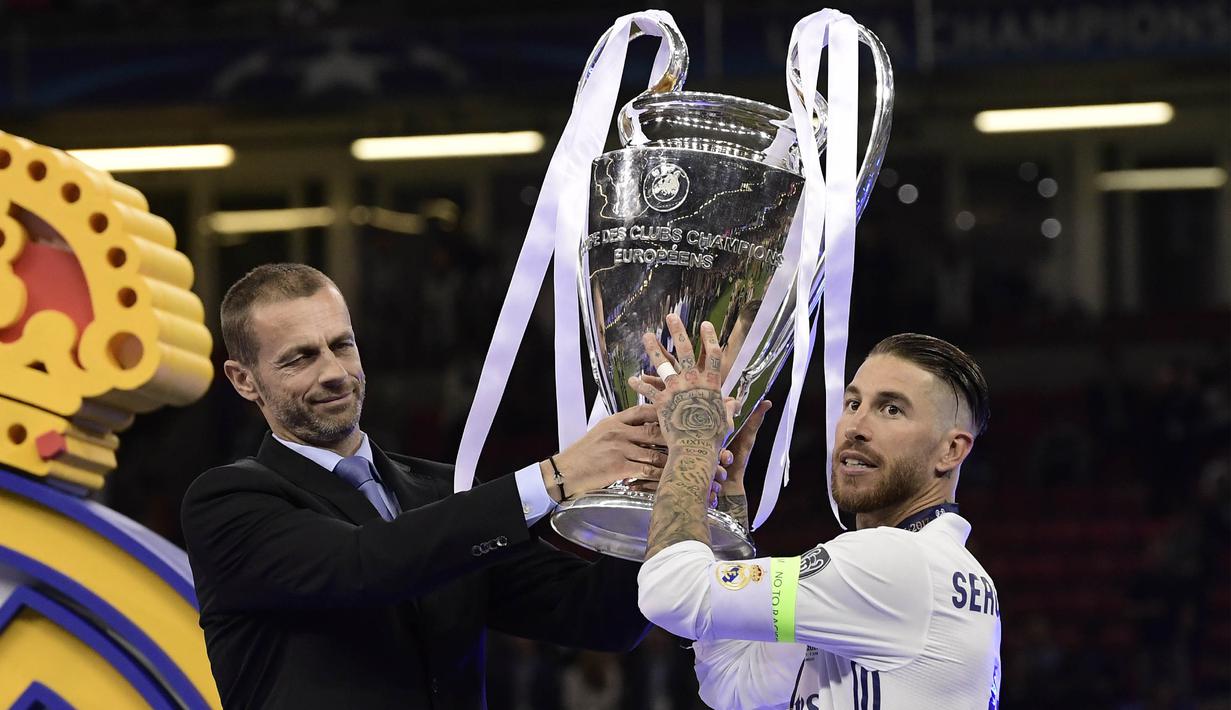 Presiden UEFA, Aleksander Ceferin, menyerahkan trofi Liga Champions kepada kapten Real Madrid, Sergio Ramos, usai menjadi juara di Stadion Millenium, Cardiff, Sabtu (3/6/2017). Madrid menang 4-1 atas Juventus. (AFP/Javier Soriano)