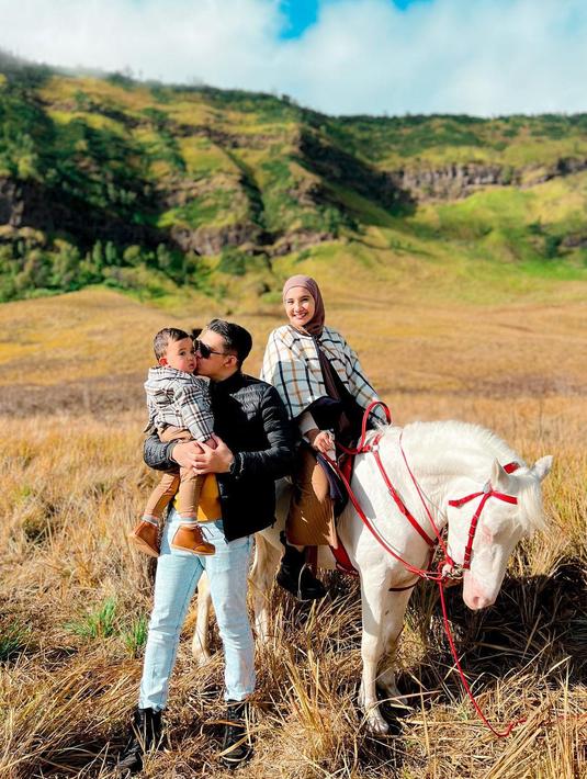 Yang ini bisa dijadikan inspirasi foto keluarga saat pelesir ke Bromo. Zaskia Sungkar menunggangi kuda putih. Sementara Irwansyah menggendong Ukkasya Muhammad Syahki. Latarnya adalah “karpet” cokelat karya Sang Khalik yang memanjang hingga menyelimuti bukit. Tiba di bukit, cokelat itu berubah warna menjadi hijau kekuningan. Duhai indahnya… (Foto: Dok. Instagram @zaskiasungkar15)
