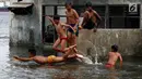 Seorang anak melompat saat bermain di Masjid yang terkena Abrasi di kawasan Muara Baru, Jakarta, Kamis (4/1). Anak-anak yang bermukim di kawasan tersebut banyak menghabiskan waktu saat berlibur sekolah untuk bermain di laut. (Liputan6.com/Johan Tallo)