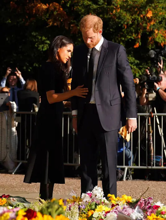 Pangeran Harry bersama sang istri Meghan Markle melihat bunga untuk mendiang Ratu Elizabeth II di luar Kastil Windsor, Windsor, Inggris, 10 September 2022. Diyakini sebelumnya Pangeran Harry dan Meghan Markle tak ada rencana untuk bertemu Pangeran William dan Kate Middleton meskipun tinggal di Frogmore Cottage, yang hanya 700 meter dari tempat tinggal sang kakak. (Kirsty O'Connor/Pool Photo via AP)