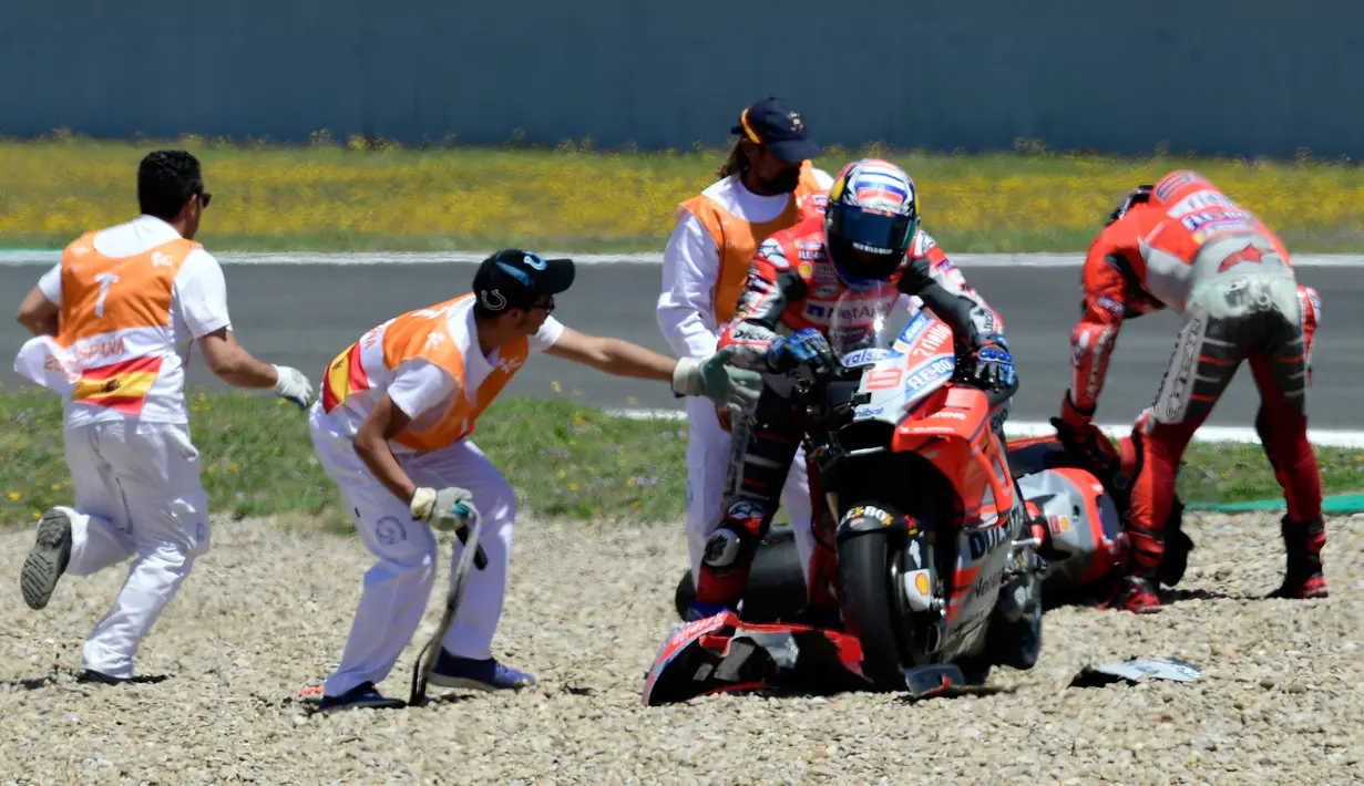 Petugas membantu pembalap Ducati, Andrea Dovizioso dan Jorge Lorenzo setelah mengalami tabrakan beruntun pada balapan MotoGP Spanyol 2018 di Sirkuit Jerez, Minggu (6/5). Mereka mengalami crash delapan lap sebelum bubaran.  (AFP/JAVIER SORIANO)