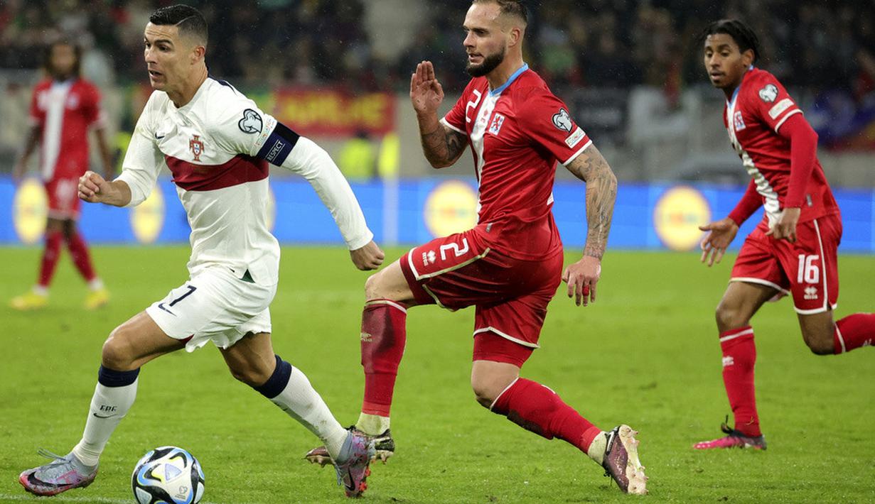 Pemain Portugal, Cristiano Ronaldo, berusaha melepaskan diri dari kawalan pemain Luksemburg, Maxime Chanot, pada matchday kedua Grup J Kualifikasi Euro 2024 di Stadion Stade de Luxembourg, Senin (27/3/2023). Portugal menang dengan skor 6-0. (AP Photo/Olivier Matthys)