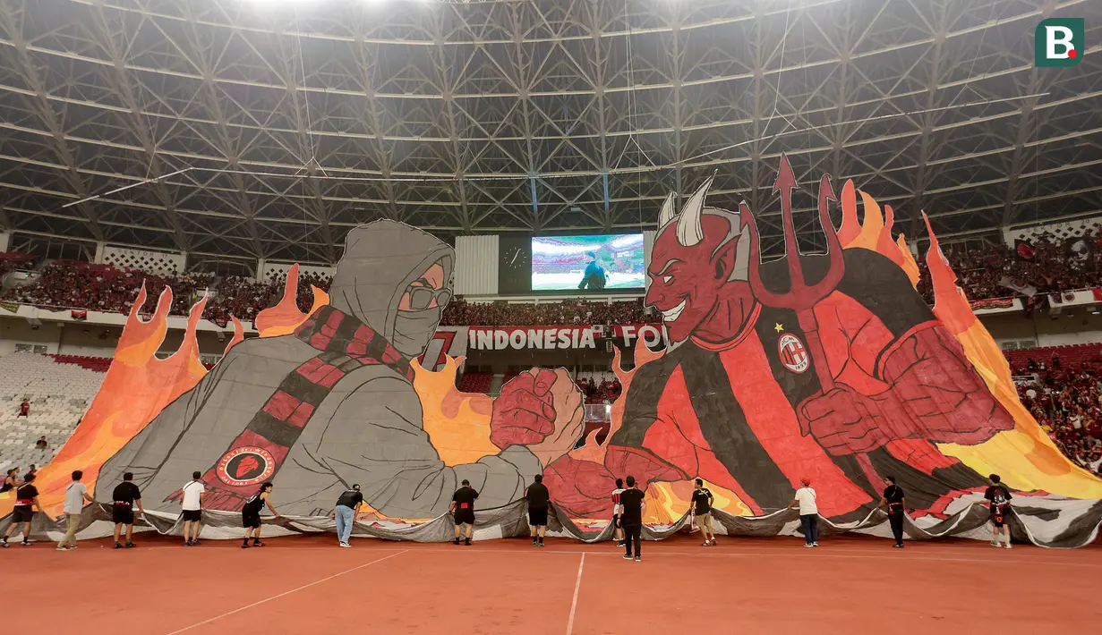 Suporter AC Milan membentangkan tifo raksasa saat memberikan dukungan kepada tim kesayangannya sebelum laga melawan Chelsea pada ajang Indonesia Super Cup 2026 di Stadion Utama Gelora Bung Karno (SUGBK), Jakarta, Sabtu (8/8/2026). Tifo bergambar sosok berjabat tangan dengan karakter iblis yang identik dengan julukan Rossoneri tersebut menjadi daya tarik di tribun dan semakin menyemarakkan atmosfer pertandingan di hadapan puluhan ribu penonton. (KapanLagi.com/Budy Santoso)