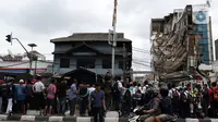 Warga menyaksikan gedung yang ambruk di Jalan Brigjen Katamso, Kota Bambu Selatan, Palmerah, Jakarta Barat, Senin (6/1/2020). Tiga orang dilaporkan terluka akibat tertima material gedung empat lantai tersebut. (Liputan6.com/Johan Tallo)