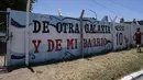 Seorang pria berjalan di samping mural yang bertuliskan dalam bahasa Spanyol: "From another galaxy and from my neighborhood,"  di jalan tempat tinggal Lionel Messi di lingkungan Las Heras di Rosario, Argentina, Rabu (14/12/2022). (AP Photo/Rodrigo Abd)