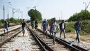 Sejumlah imigran berjalan menyusuri rel kereta api saat perjalanan menuju Gevgelija, wilayah perbatasan Macedonia-Yunani, Kamis (9/7/2015). Mereka menempuh ribuan kilometer agar dapat mengejar kereta api tujuan Serbia. (AFP PHOTO/Robert ATANASOVSKI)