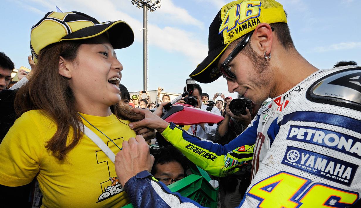 Pebalap MotoGP, Valentino Rossi, memberikan tanda tangan kepada fans wanita saat GP Jepang di Sirkuit Motegi, Jepang, Jumat (1/10/2010). (AFP/Toru Yamanaka)