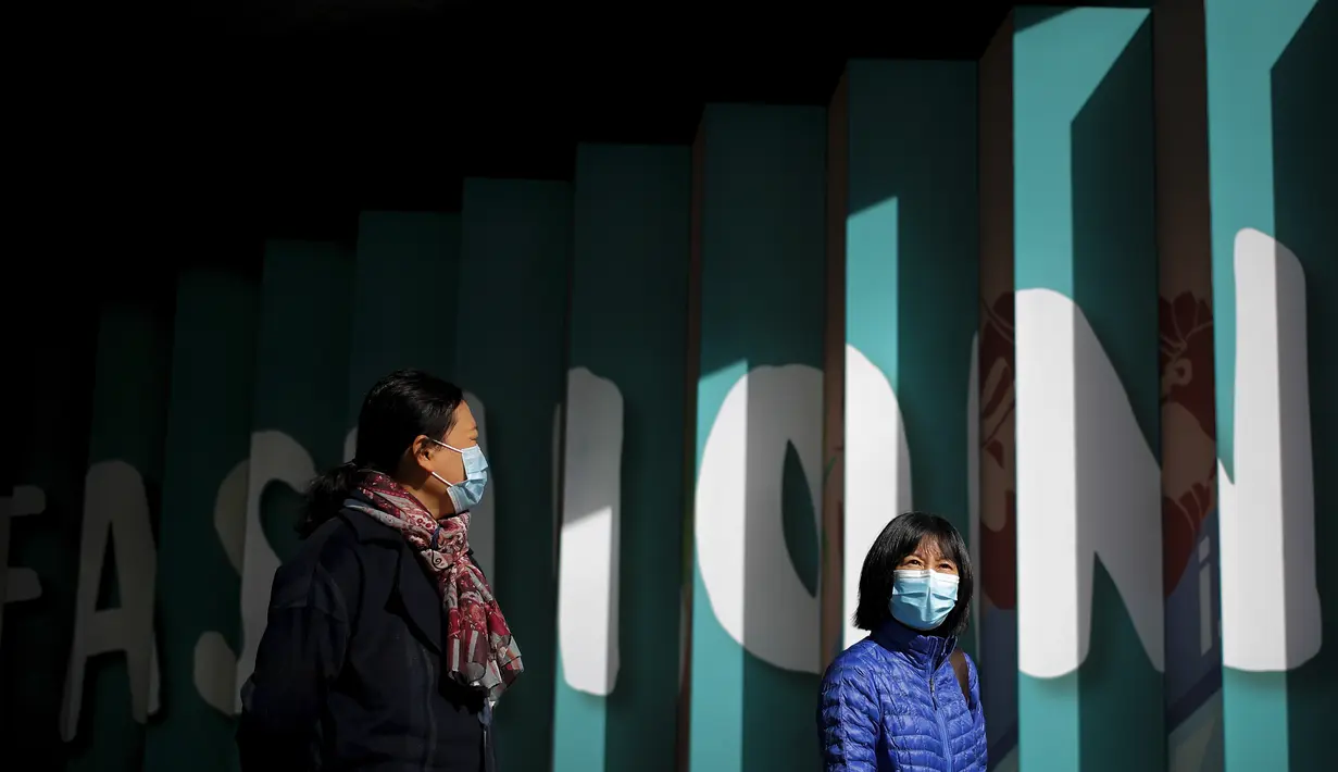 Wanita yang memakai masker untuk mencegah virus corona berjalan melalui pusat perbelanjaan populer ibu kota di Beijing, Selasa (3/11/2020). Sementara virus Corona masih melonjak di seluruh dunia dengan jumlah kematian yang terus meningkat.  (AP Photo/Andy Wong)