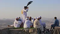 Peziarah muslim berfoto di Jabal al-Noor atau Gunung Cahaya yang menghadap ke Kota Suci Mekkah, Arab Saudi, 5 Juli 2022. Satu juta orang, termasuk 850 ribu dari luar negeri, diizinkan untuk berpartisipasi dalam haji tahun ini setelah dua tahun terakhir jumlahnya dikurangi secara drastis karena pandemi virus corona COVID-19. (Christina ASSI/AFP)