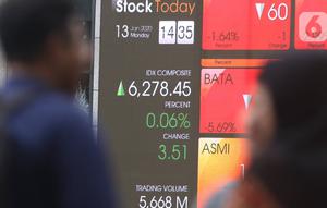 Pejalan kaki melintas dekat layar pergerakan Indeks Harga Saham Gabungan (IHSG) di kawasan Jakarta, Senin (13/1/2020). IHSG sore ini ditutup di zona hijau pada level 6.296 naik 21,62 poin atau 0,34 persen. (Liputan6.com/Angga Yuniar)