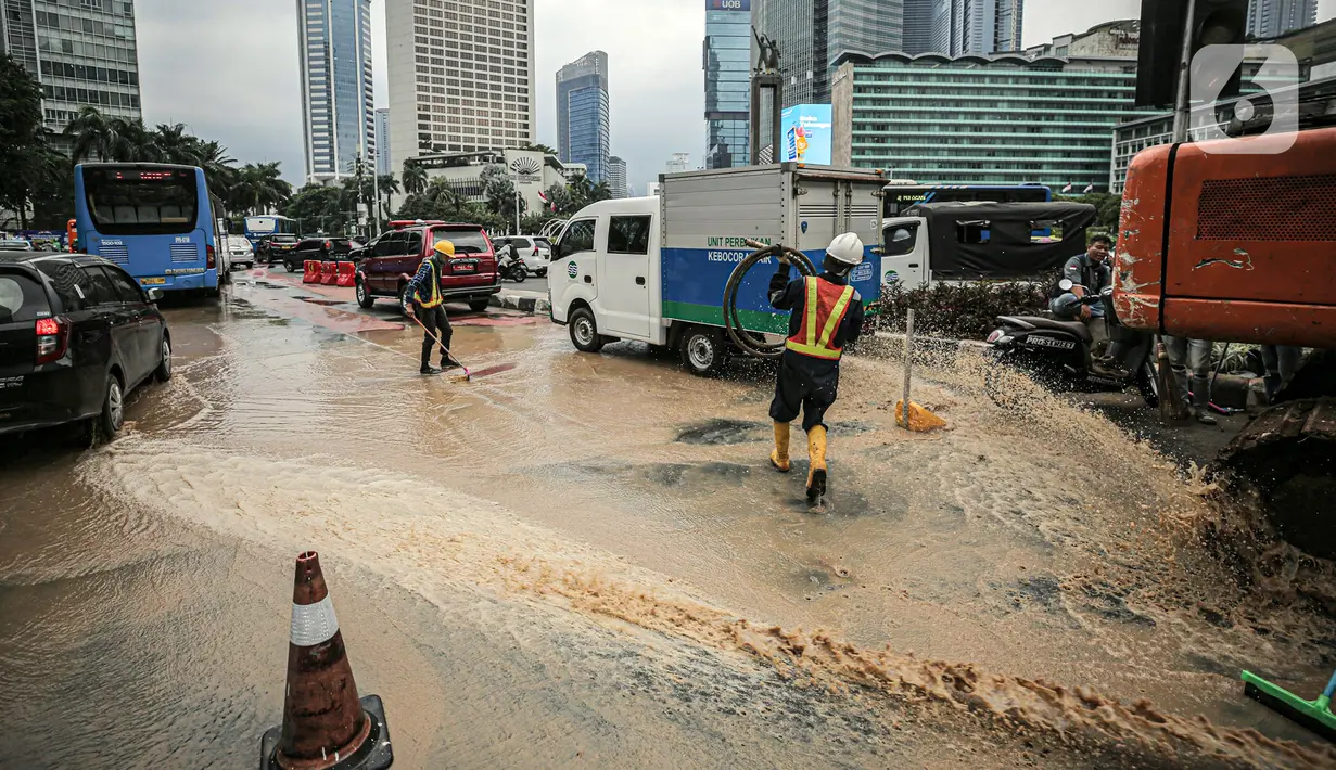 Petugas membersihkan jalan dari genangan air akibat kebocoran saluran pipa air di kawasan Bundaran Hotel Indonesia (HI), Jakarta, Selasa (11/10/2022). Kebocoran pipa air diduga terimbas proyek revitalisasi Halte Bundaran Hotel Indonesia. (Liputan6.com/Faizal Fanani)