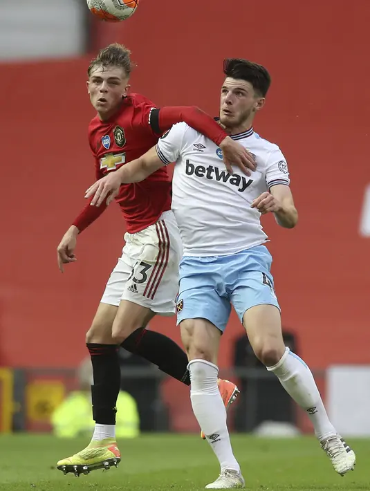 Pemain Manchester United Brandon Williams (kiri) berebut bola udara dengan pemain West Ham United  Declan Rice pada pertandingan Liga Inggris di Old Trafford, Manchester, Inggris, Rabu (22/7/2020). Pertandingan berakhir dengan skor 1-1. (Martin Rickett/Pool via AP)
