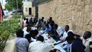 Sejumlah pria Sudan menikmati makanan buka puasa selama bulan suci Ramadan di depan kedubes Inggris di ibukota Khartoum (23/5/2019). Duta Besar Inggris untuk Sudan, Irfan Sidiq menggelar buka puasa bersama di ibu kota tersebut. (AFP Photo/Ebrahim Hamid)