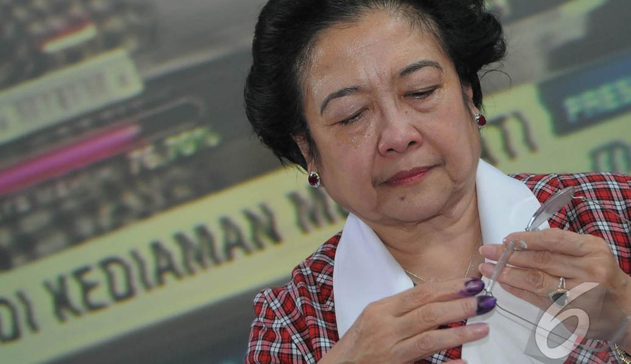 Megawati membersihkan kacamatanya yang terkena tetesan air mata haru saat mengetahui kemenangan Jokowi melalui hasil hitung cepat, Jakarta, Rabu (9/7/2014) (Liputan6.com/Herman Zakharia) 