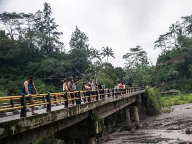 Sejumlah turis melihat aliran lahar dingin Gunung Agung di Karangasem, Bali (29/11). Ribuan turis diperkirakan akan meninggalkan Bali pada 30 November menyusul penutupan bandara akibat Gunung Agung Meletus. (AFP Photo/Juni Kriswanto)