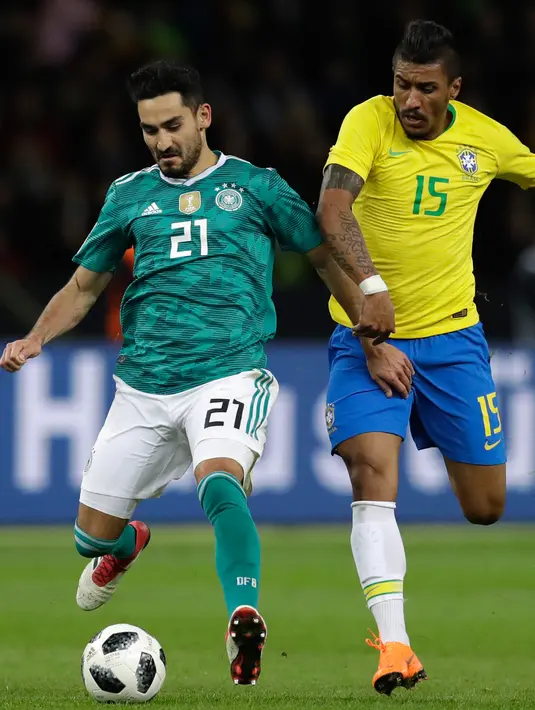 Pemain timnas  Jerman, Ilkay Gundogan berebut bola dengan pemain timnas Brasil, Paulinho dalam laga uji coba di Olympiastadion Berlin, Selasa (27/3). Brasil sukses menaklukkan Jerman dengan skor 1-0. (AP Photo/Michael Sohn)