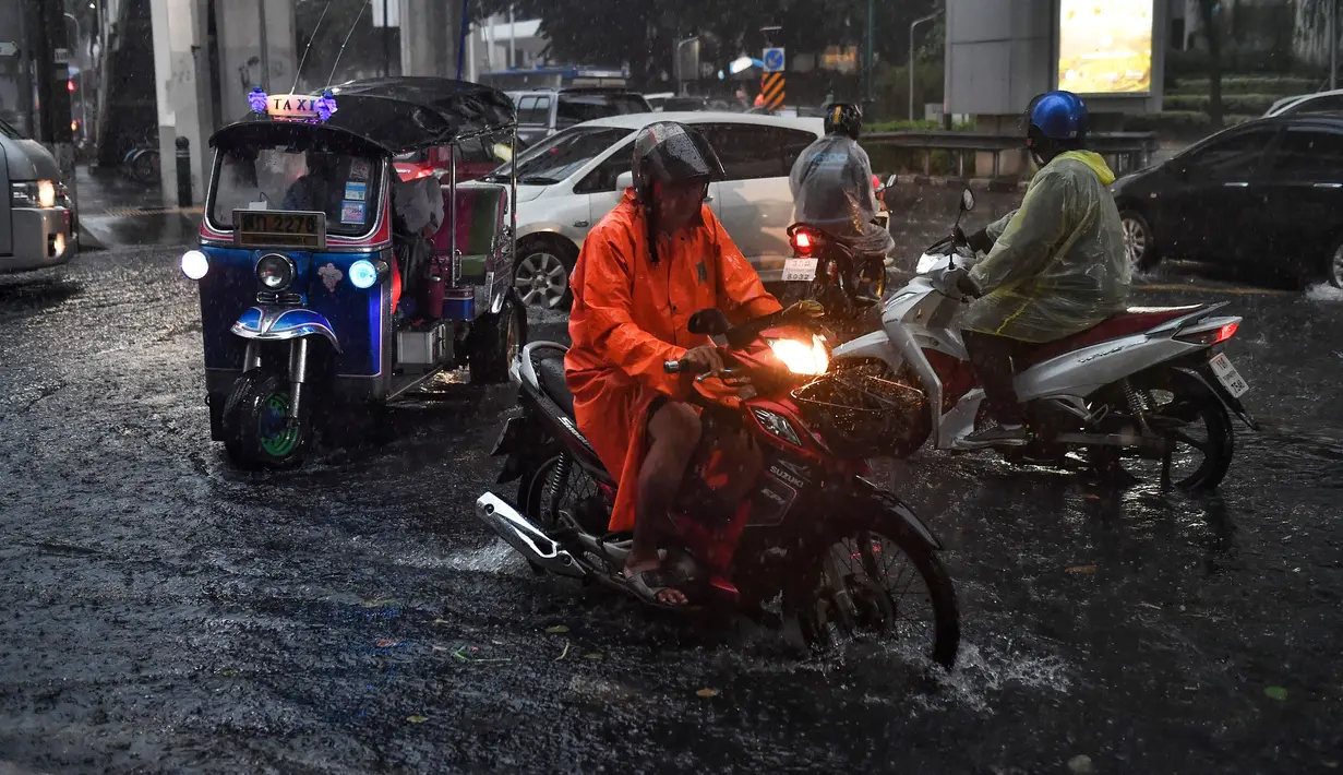 Pengendara berkendara melalui jalan yang banjir saat hujan deras di Bangkok (23/9/2020). (AFP/Mladen Antonov)