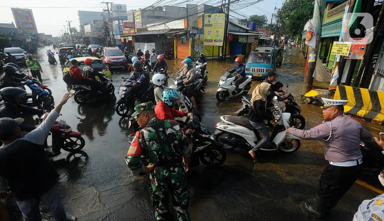 Petugas kepolisian mengatur lalu lintas saat banjir di kawasan tersebut.  (merdeka.com/Arie Basuki)