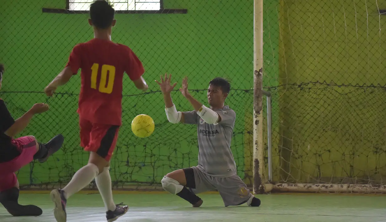 Seorang kiper, Eman Sulaeman mencoba menangkap bola dalam pertandingan futsal di Indramayu, 3 Februari 2018. Keterbatasan fisik tidak menjadi penghalang Eman untuk melakukan aktivitas berat, termasuk berolahraga, khususnya sepak bola. (ADEK BERRY/AFP)