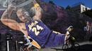 Pesepeda melintas di depan lukisan mural bintang LA Lakers, Kobe Bryant di Los Angeles, California, Selasa (26/1/2021). Lukisan dibuat untuk mengenang 1 tahun tragedi kecelakaan helikopter yang menewaskan Kobe Bryant bersama putrinya, Gianna. (Getty Images via AFP/Harry How)