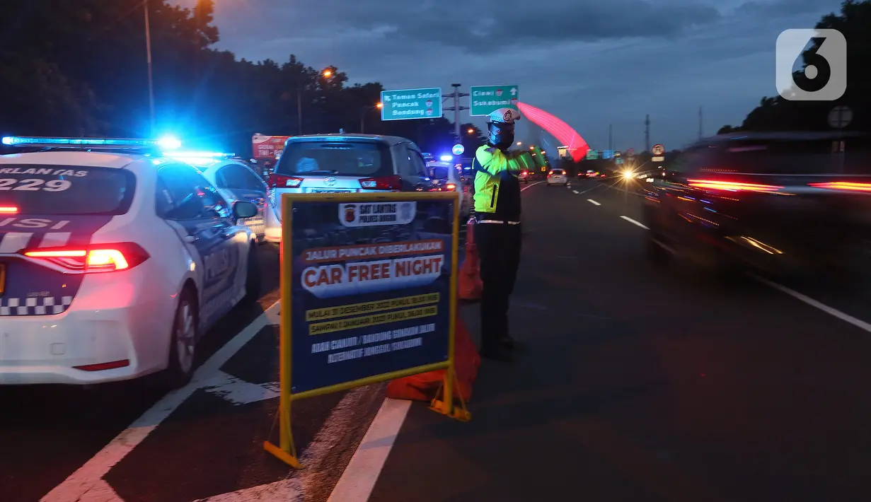 Petugas dari Polres Bogor memasang rambu penutupan jalan di pintu keluar Tol Gadog, Bogor, Sabtu (31/12/2022). Penutupan jalan jalur Puncak Bogor untuk gelaran Car Free Night dimulai sejak pukul 18.00 WIBdan dibuka kembali esok pagi pukul 06.00 WIB. (merdeka.com/Arie Basuki)