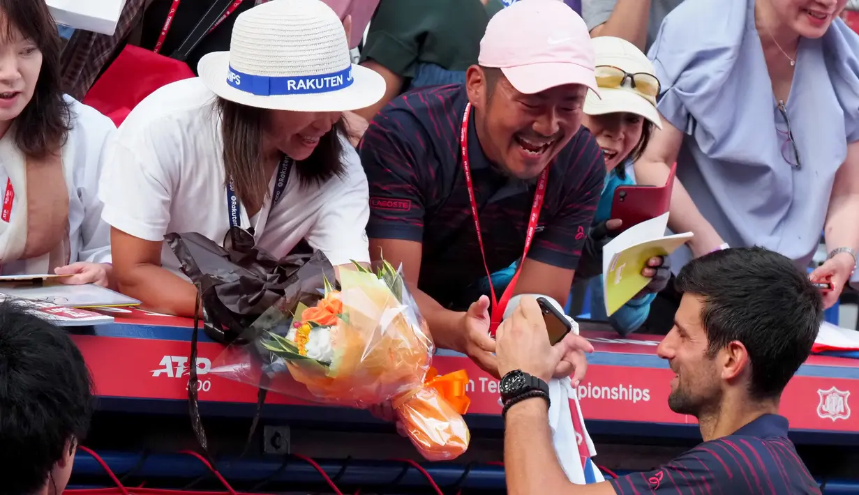 Petenis Serbia, Novak Djokovic memberikan tanda tangan kepada penggemar usai pertandingan melawna Lucas Pouille dari Prancis di Tenis Jepang Terbuka 2019 di Ariake Coliseum, Tokyo, Jumat (4/10/2019). Djokovic menang dengan skor 6-1, 6-2 atas Pouille. (AFP Photo/Toshifumi Kitamura)