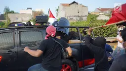 Aparat kepolisian berlindung di balik tameng saat kendaraan yang dinaiki diserang massa pelajar dalam unjuk rasa di sekitar kawasan DPR RI, Jakarta, Senin (30/9/2019). Sempat terjadi kericuhan akibat peristiwa tersebut hingga menyebabkan jalan tol ditutup. (Liputan6.com/Immanuel Antonius)