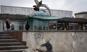 Orang-orang melewati karya seni dari seniman jalanan terkenal TvBoy yang menggambarkan seorang anak laki-laki sedang menghangatkan tangannya dengan api pada dinding yang rusak berat akibat serangan Rusia di Kota Bucha, Ukraina, 30 Januari 2023. Karya seni yang dibuat untuk menghormati para korban perang Rusia-Ukraina tersebut mengandung pesan kelahiran kembali dan harapan serta berharap agar konflik segera berakhir. (AP Photo/Efrem Lukatsky)