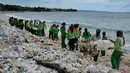 Pekerja mengumpulkan sampah plastik saat membersihkan pantai Kuta dekat Denpasar di pulau wisata Bali (6/1/2021). Sampah kemudian dimasukkan ke dalam truk untuk dibawa ke tempat pembuangan sampah. (AFP/Sonny Tumbelaka)