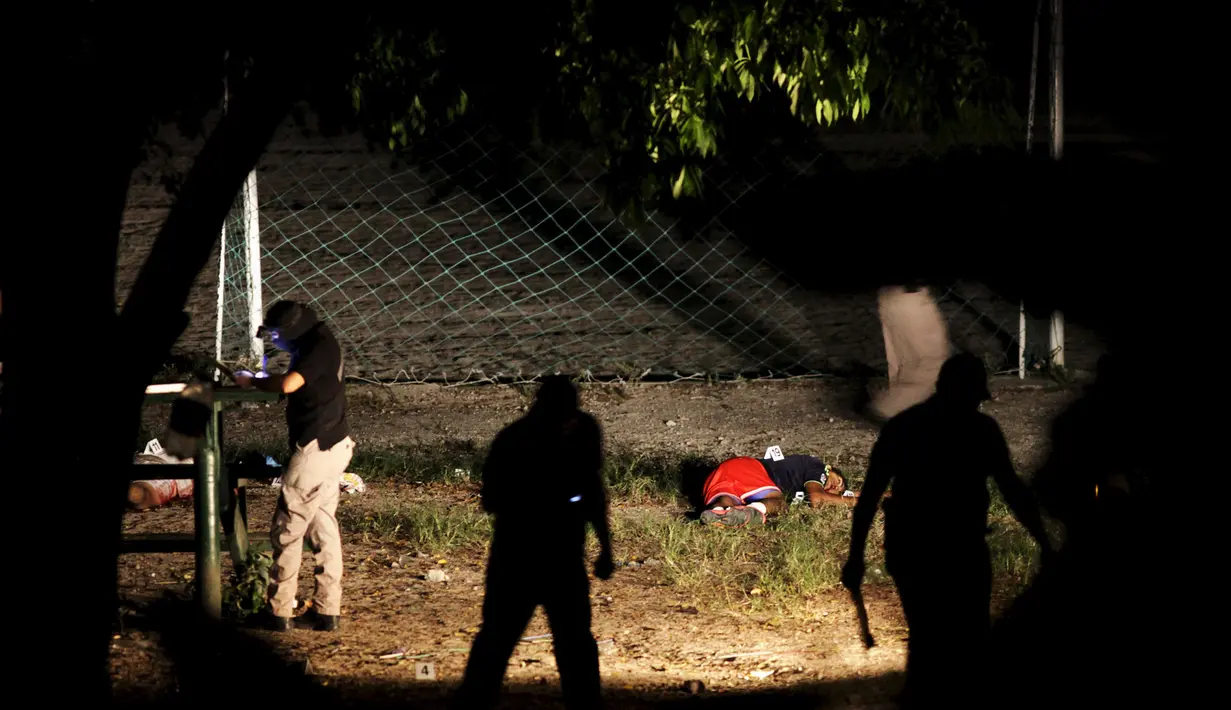 Polisi memeriksa salah satu korban pembunuhan di sebuah lapangan sepak bola, Cuscatancingo , El Salvador, Minggu (2/8/2015). Mara Salvatrucha adalah sebuah organisasi internasional kelompok kriminal berbahaya di negara ini. (REUTERS/Jose Cabezas)