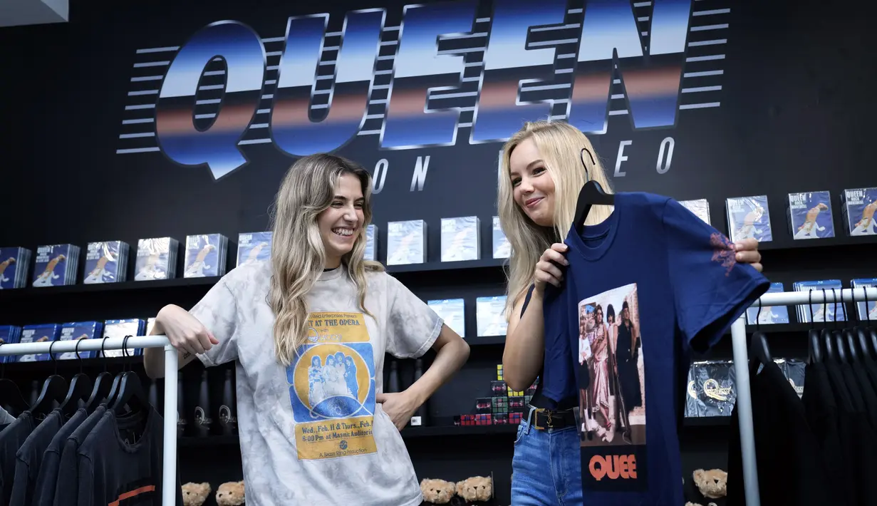 Dua perempuan memegang t-shirt di toko baru yang didedikasikan untuk menjual merchandise resmi band rock Queen sebelum dibuka di London, Senin (27/9/2021). Band legendaris Queen membuka toko pop-up di Carnaby Street untuk menandai lima dekade mereka di kancah musik. (AP Photo/Alastair Grant)