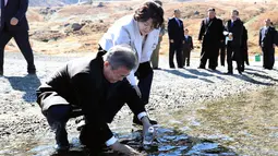 Presiden Korsel Moon Jae-in ditemani istrinya, Kim Jung-sook memasukkan air kawah ke dalam botol di Gunung Paektu, Korut, Kamis (20/9). Gunung ini menjadi propaganda untuk melegitimasi tiga generasi pemerintahan Kims. (Pyongyang Press Corps Pool via AP)