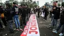 Demonstran membentangkan spanduk berisi pesan tuntutan saat berunjuk rasa di depan Gedung MPR/DPR/DPD, Jalan Gatot Subroto, Jakarta, Jumat (20/5/2022). Demonstran menuntut berbagai isu, di antaranya Omnibus Law dan penurunan harga sembako serta bahan bakar minyak (BBM). (Liputan6.com/Johan Tallo)