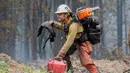 <p>Seorang petugas pemadam kebakaran bekerja untuk menahan api Cedar Creek di sebelah timur Oakridge, Oregon, Senin (12/9/2022). Kebakaran menghabiskan lahan setara dengan dua kali ukuran Ibu Kota AS, Washington. (Photo by Dan Morrison/AFP)</p>