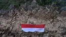 Sekelompok mahasiswa mengibarkan bendera Merah Putih berukuran besar menjelang perayaan Hari Ulang Tahun ke-77 Republik Indonesia di Pantai Lhoknga, Aceh, 16 Agustus 2022. Pengibaran bendera Merah Putih berukuran besar yang dilakukan pada sebuah tebing ini untuk memeriahkan Hari Ulang Tahun ke-77 Republik Indonesia. (CHAIDEER MAHYUDDIN/AFP)