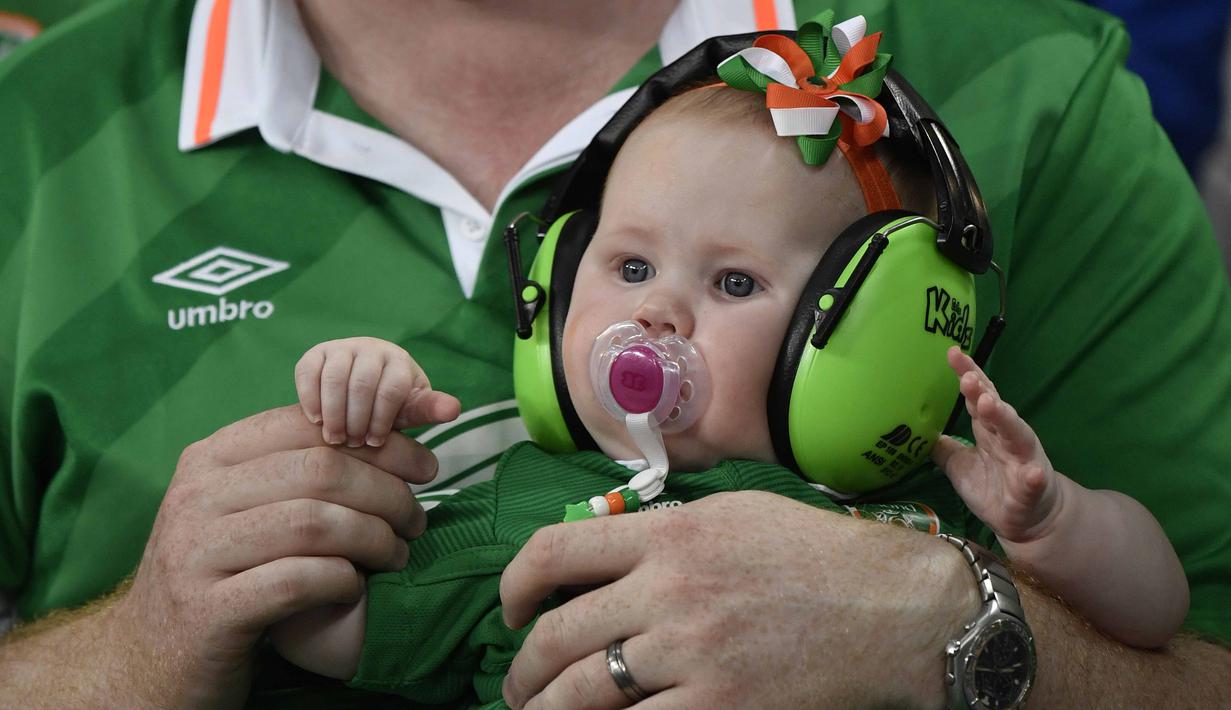 Suporter cilik Republik Irlandia ini tengah menyaksikan laga timnya dengan menggunakan peredang suara pada telinga saat timnya melawan Italia di Stadion Pierre-Mauroy, Villeneuve-d'Ascq,  (22/6/2016). (AFP/Philippe Lopez)