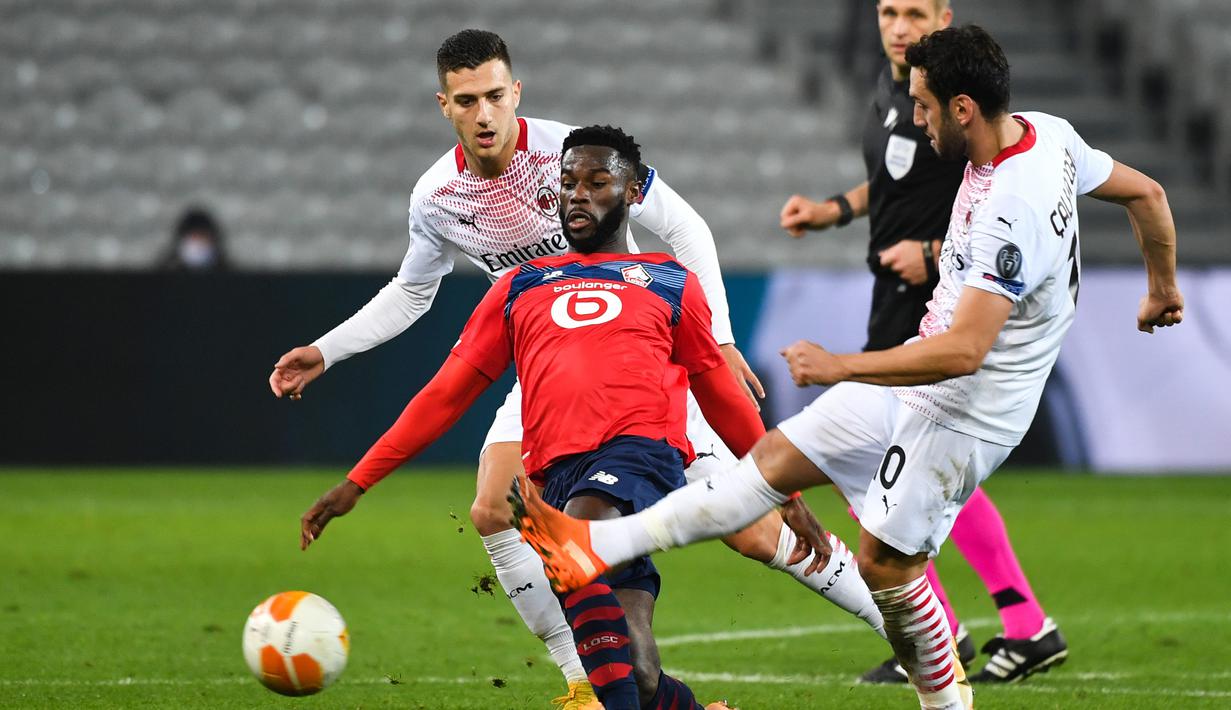 Gelandang Lille, Jonathan Bamba, berusaha melewati pemain AC Milan pada laga lanjutan laga lanjutan Liga Europa di Stade Pierre Mauroy, Jumat (27/11/2020) dini hari WIB. AC Milan bermain imbang 1-1 menghadapi Lille. (AFP/Dennis Charlet/pool)