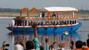 Presiden Prancis Emmanuel Macron bersama PM India Narendra Modi melambaikan tangan saat mereka naik perahu di Sungai Gangga di Varanasi, India, Senin (12/3). Perahu yang membawa keduanya berhias bunga marigold. (AP Photo/Rajesh Kumar Singh)
