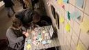 Sejumlah warga menulis di post-it sebagai bagian 'subway therapy' di dinding stasiun Union Square, New York, Kamis (10/11). Subway therapy digunakan kaum komuter yang kesal dan kecewa dengan terpilihnya Donald Trump sebagai Presiden AS (DREW ANGERER/AFP)