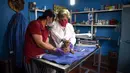 Dokter hewan memeriksa anak harimau bengal yang baru lahir di Pusat Penyelamatan dan Rehabilitasi Satwa Liar "BioZoo" di negara bagian Veracruz, Meksiko, 5 April 2020. Bayi harimau yang lahir pada 14 Maret 2020 lalu ini dinamai 'Covid' di tengah pandemi wabah virus corona. (VICTORIA RAZO/AFP)