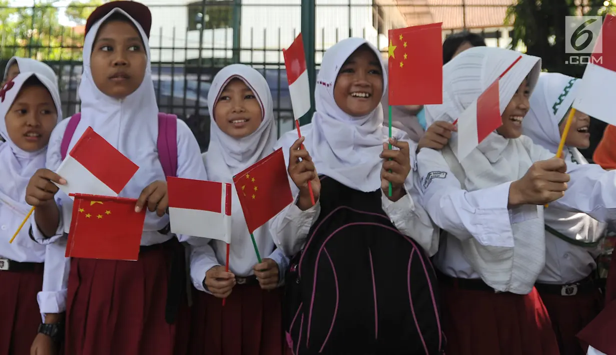 Sejumlah murid menyambut kedatangan PM China Li Keqiang di kawasan Istana Bogor, Senin (7/5). Li akan melakukan pertemuan bilateral dengan Presiden Jokowi membahas proyek pembangunan jaringan kereta api cepat Jakarta-Bandung.  (Merdeka.com/Arie Basuki)