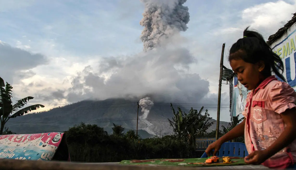 Seorang anak terlihat bermain saat gunung berapi Gunung Sinabung mengeluarkan abu vulkanik di Karo, Sumatra Utara (11/12). Gunung Sinabung kembali aktif pada tahun 2010 untuk pertama kalinya dalam 400 tahun. (AFP Photo/Ivan Damanik)