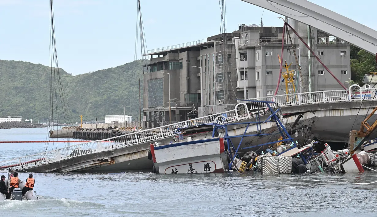 Tim penyelamat menggunakan kapal kecil bersiap mengevakuasi dalam pekerjaan kapal di lokasi jembatan yang ambruk di pelabuhan Nanfangao di kota Suao (1/10/2019). Tiga perahu nelayan yang tertimpa serta kendaraan di atas jembatan yang rusak, termasuk truk tangki. (AFP Photo/Sam Yeh)