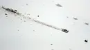 Petugas mendekati helikopter yang jatuh di kawasan ski Campo Felice, Italia, Selasa (24/1). Berdasarkan laporan awal helikopter tersebut jatuh usai menjemput seseorang yang terluka akibat kecelakaan ski. (AP Photo)
