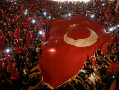 Pendukung Presiden Turki, Tayyip Erdogan mengibarkan bendera nasional mereka ketika berkumpul di Taksim Square, pusat kota Istanbul, Sabtu (16/7). Ratusan warga turun ke jalan untuk merayakan kegagalan kudeta militer di Turki. (REUTERS/Huseyin Aldemir)