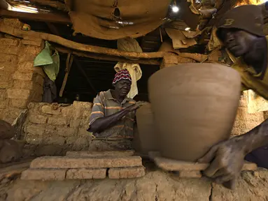 Seorang perajin Sudan membentuk sepotong tembikar di sebuah bengkel di Omdourman, di pinggiran barat ibu kota Khartoum (19/1/2022). Pot tanah liat tersebut nantinya akan dipajang untuk dijual. (AFP/Ashraf Shazly)
