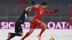 Gelandang Bayern Munich, Leroy Sane (kanan) menggiring bola dibayangi bek Arminia Bielefeld, Jacob Barrett Laursen dalam laga lanjutan Liga Jerman 2020/21 pekan ke-21 di Allianz Arena, Munich, Senin (15/2/2021). Bayern Munich bermain imbang 3-3 dengan Arminia Bielefeld. (AFP/Christof Stache/Pool)