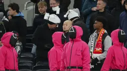 Orang-orang berpakaian seperti penjaga Squid Games dengan berdiri di area penonton selama pertandingan lanjutan Liga Inggris 2024/2025 antara Tottenham Hotspur melawan Liverpool di Stadion Tottenham Hotspur, London, Inggris Minggu (22/12/2024). Seperti diketahui, aksi tersebut ternyata merupakan promo musim kedua serial Korea Selatan tersebut. (AP Photo/Dave Shopland)